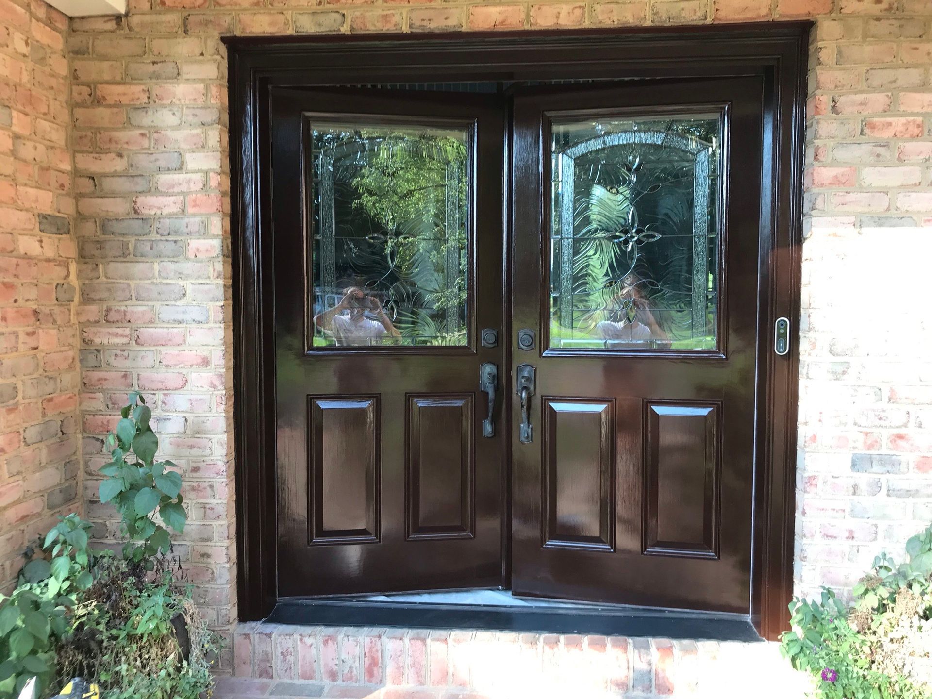 A brown double door is sitting on a brick wall.