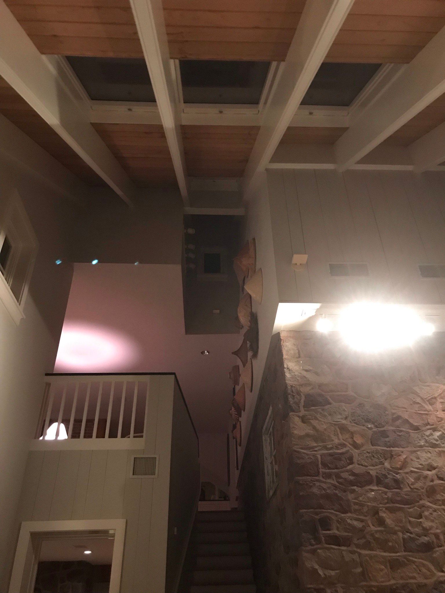 A staircase with a wooden ceiling and a stone wall