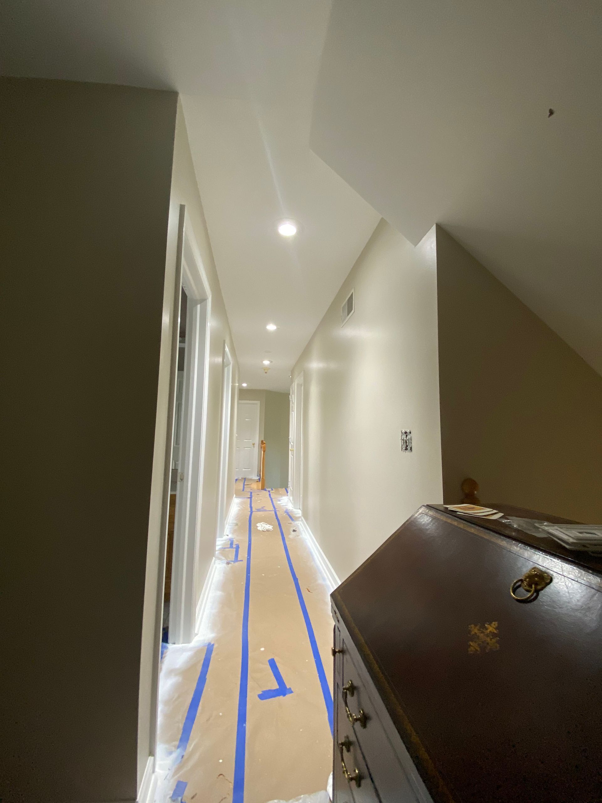 A long hallway with a dresser in the middle of it