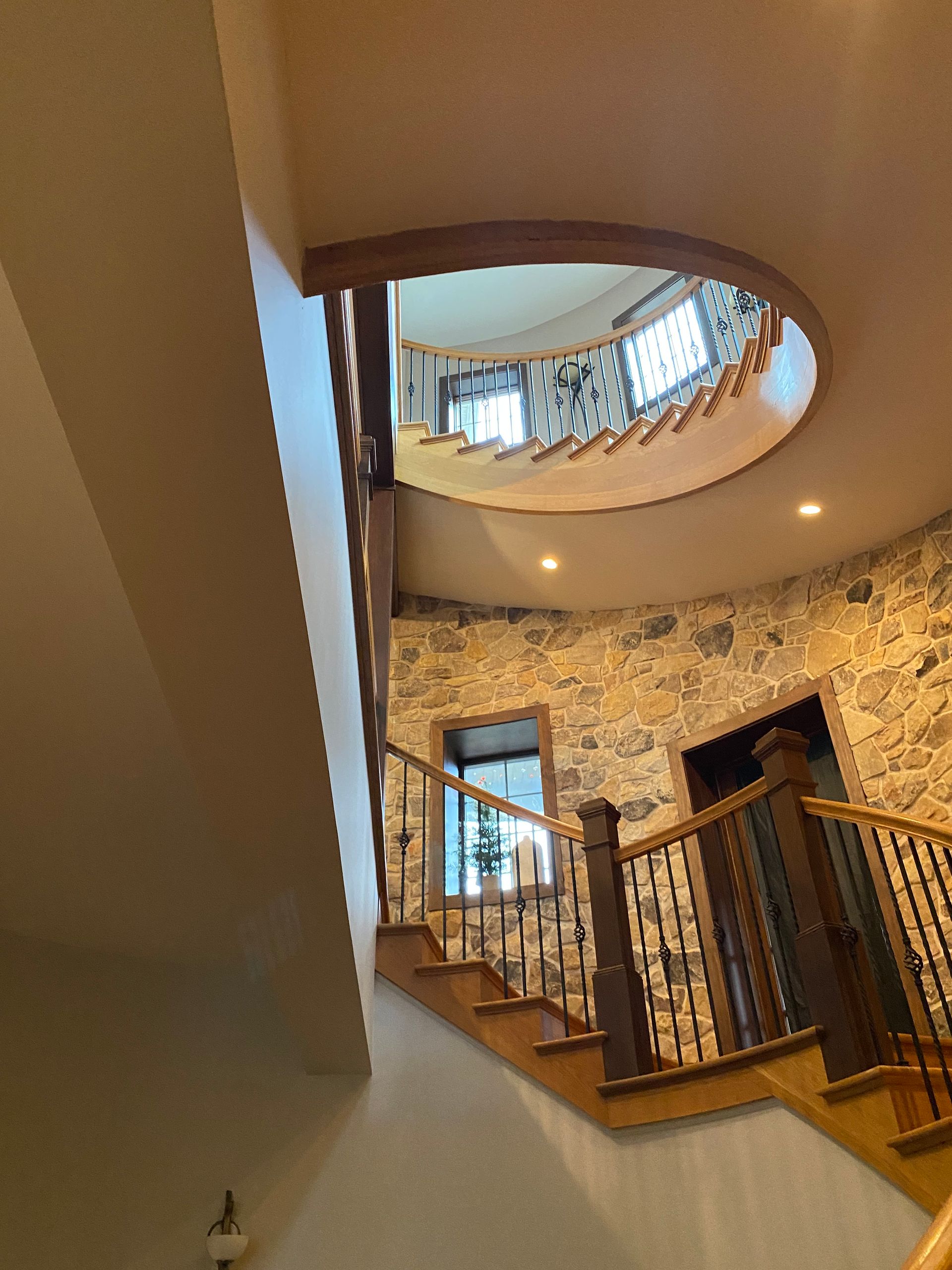 A spiral staircase in a house with a stone wall