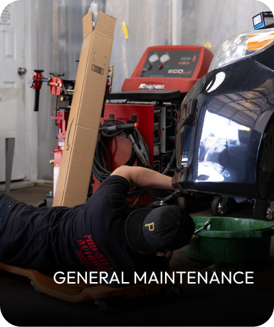 Mechanic under a car, working on general maintenance in a garage. | Mid Atlantic Autoworks