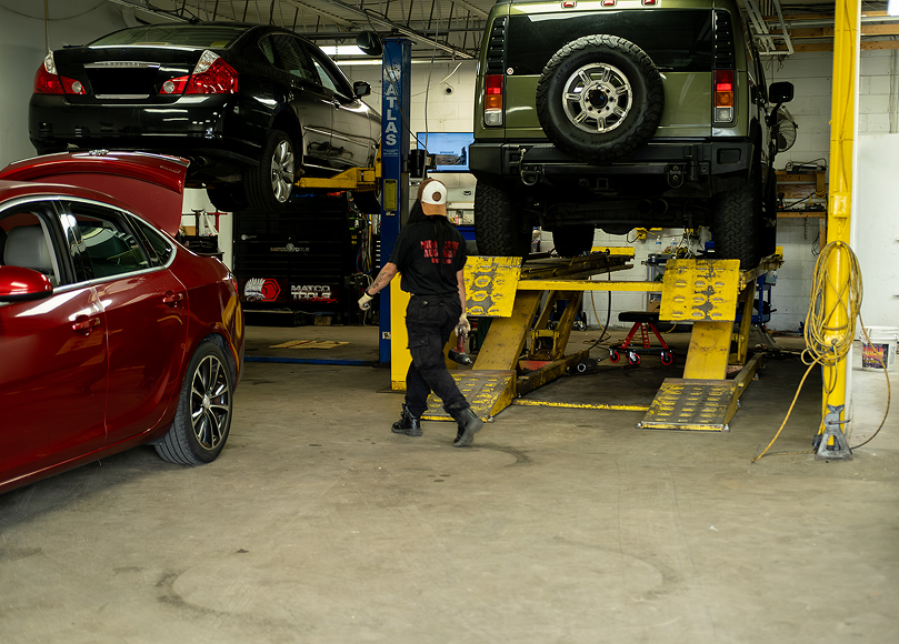 Mechanic walking in an auto repair shop with cars on lifts. | Mid Atlantic Autoworks