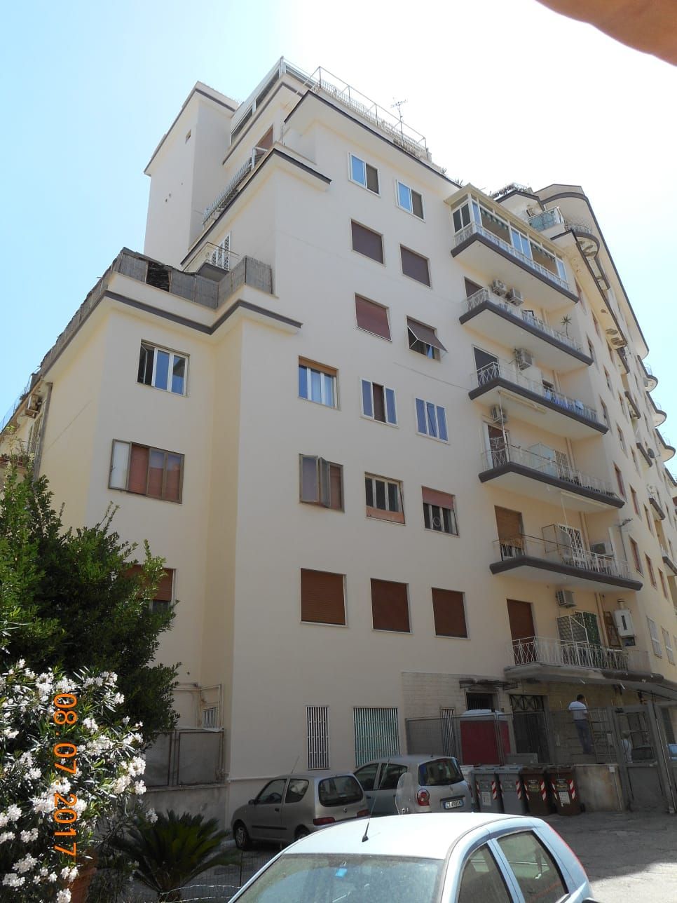 Un'auto bianca è parcheggiata davanti a un edificio alto