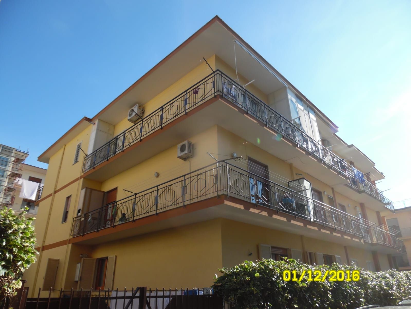 Un edificio giallo con balconi e un cielo azzurro sullo sfondo