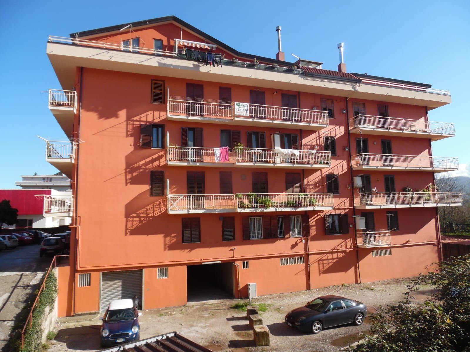 Un grande edificio arancione con auto parcheggiate di fronte