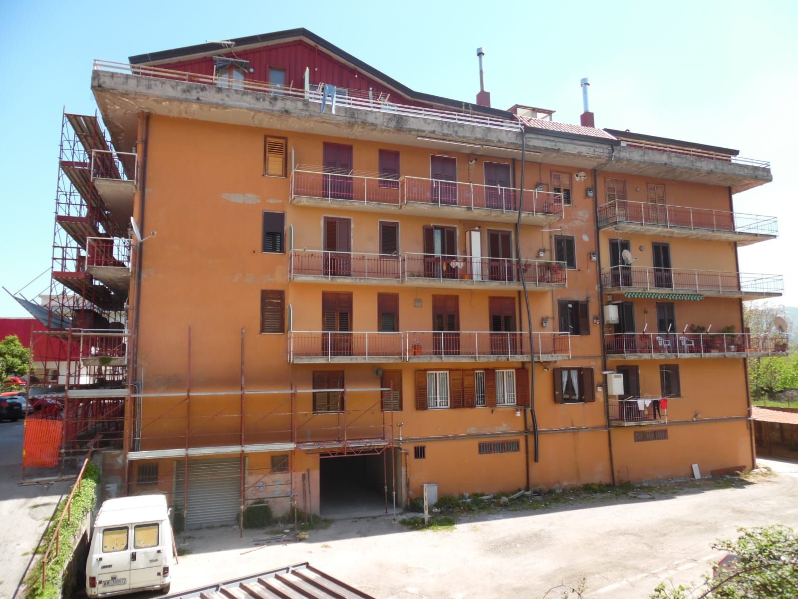 Un grande edificio arancione con un furgone bianco parcheggiato davanti.