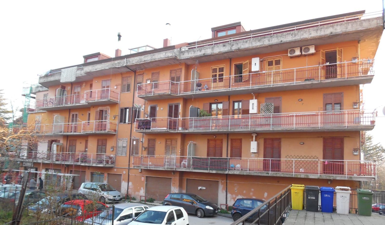 Un grande condominio con le auto parcheggiate davanti.