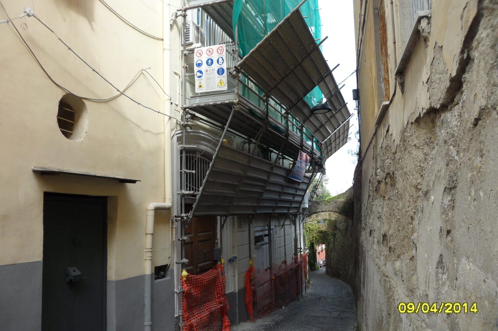 Uno stretto vicolo con impalcature sul lato di un edificio