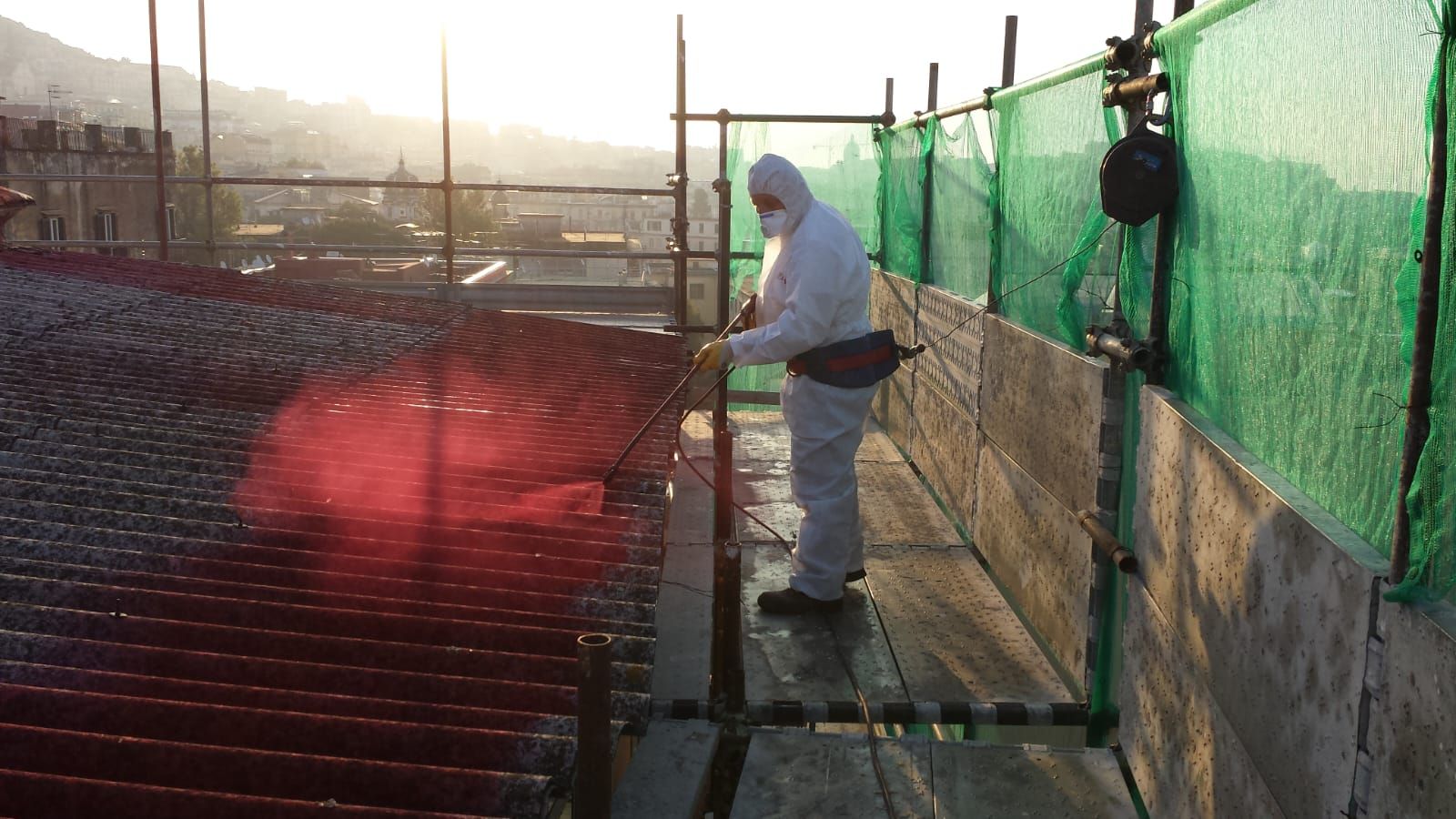 Un uomo con una tuta protettiva sta lavorando su un tetto.