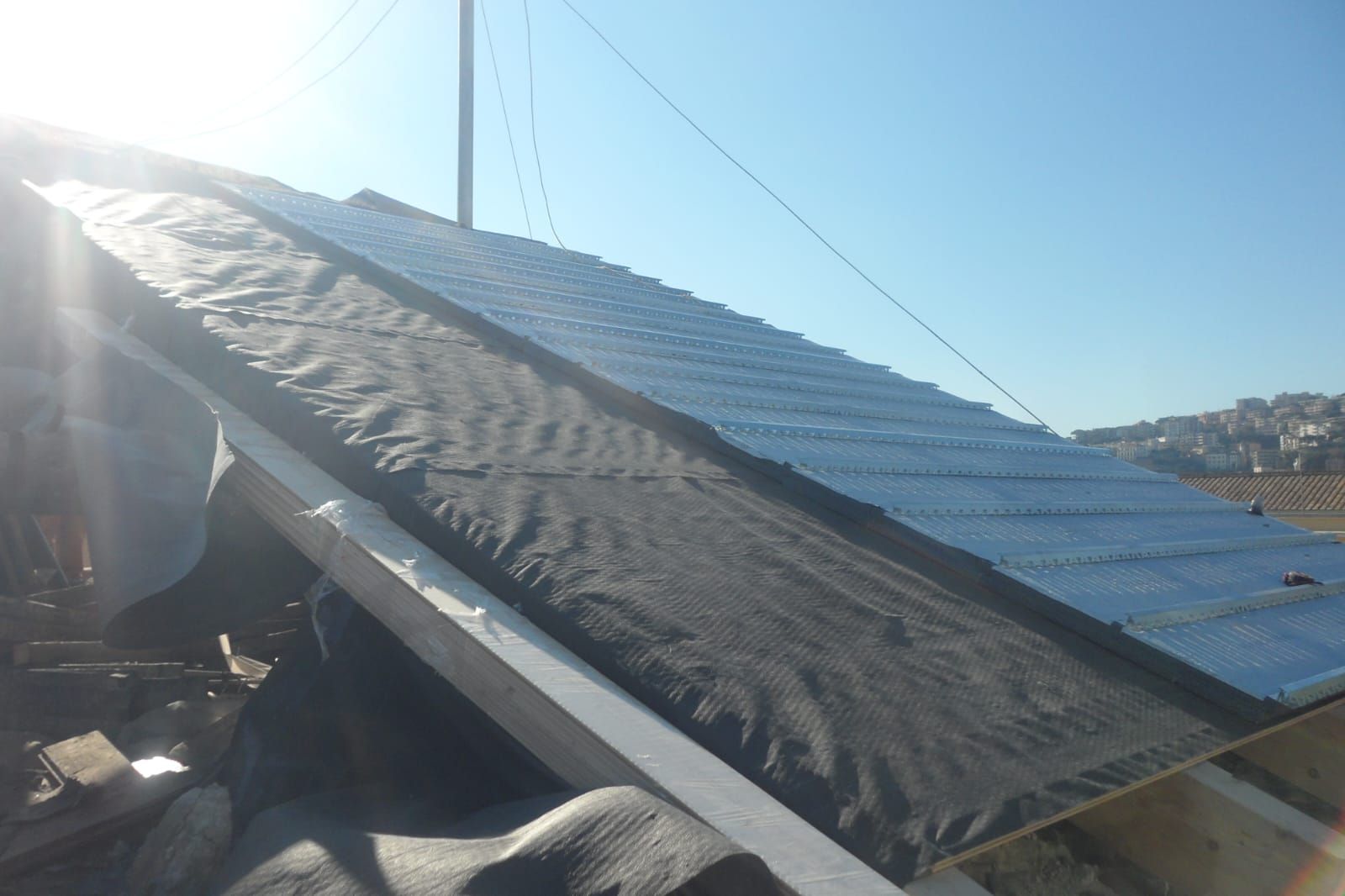 Una persona sta lavorando su un tetto coperto da un telo.