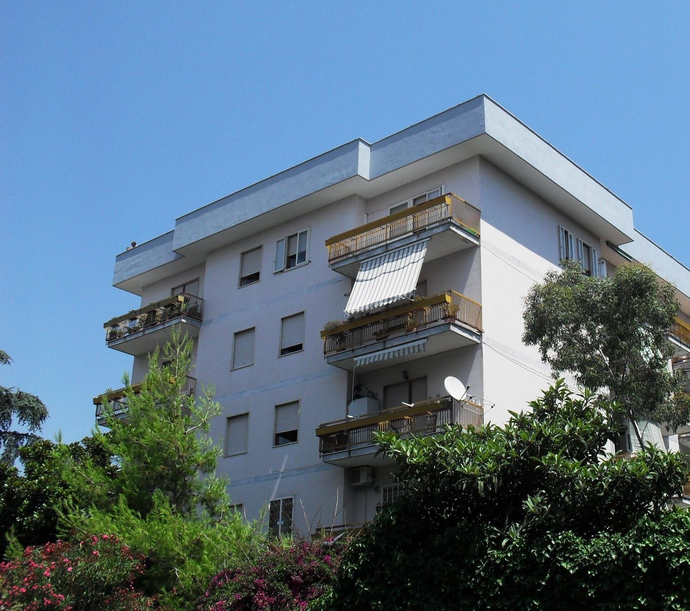 Un edificio bianco con balconi e un cielo azzurro sullo sfondo