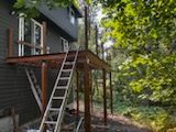 A ladder is sitting on a wooden deck next to a house.