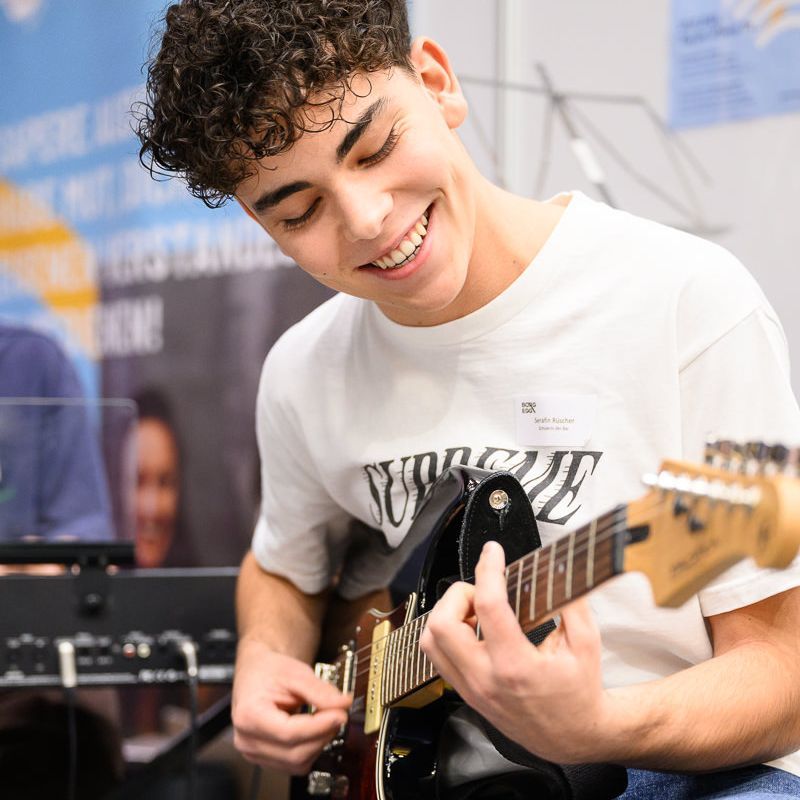 Junge Frau singt und spielt Akustikgitarre auf der Bühne.