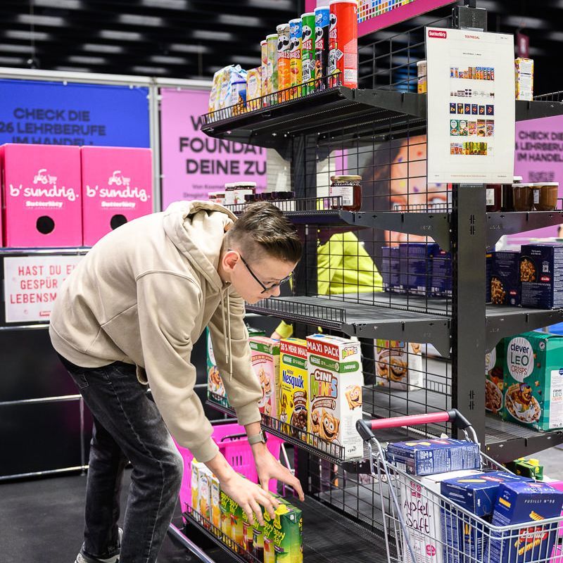 Junge im gelben Kapuzenpulli passt VR-Headset in einem roten Raum an, andere schauen zu.