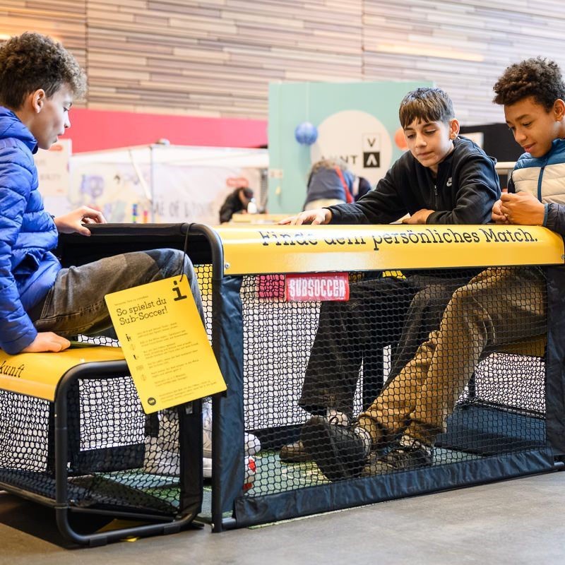 Frau und Kind arbeiten gemeinsam an einem Projekt an einem Tisch, beide konzentriert und engagiert.