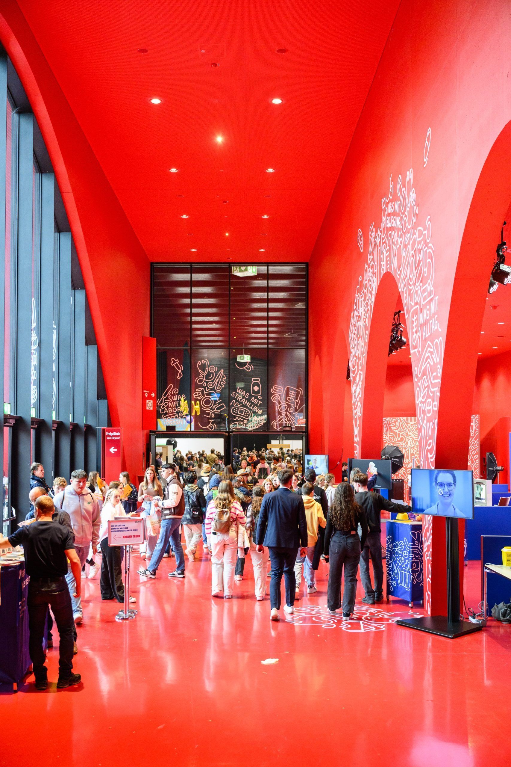Roter Innenraum mit Menschenmenge. Menschen gehen in einem hellen Raum.