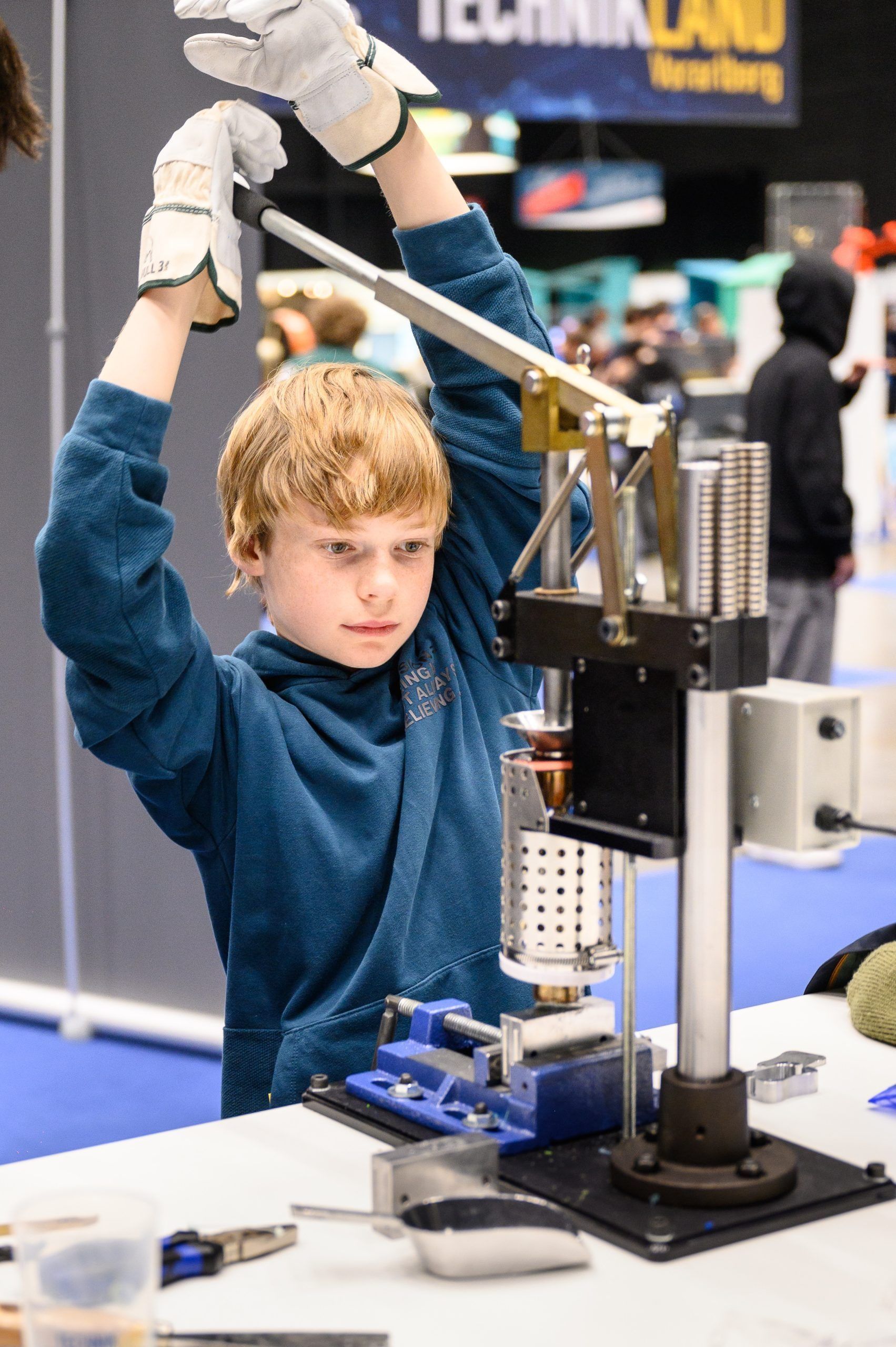Junge mit Handschuhen bedient Maschinen bei einer Veranstaltung.