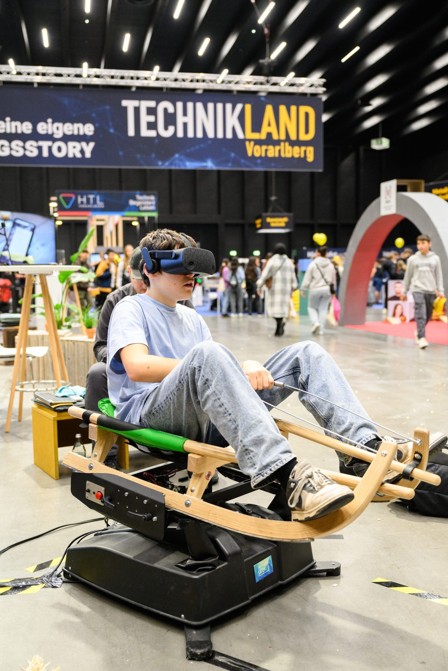 Mann mit VR-Headset sitzt auf einem Bewegungssimulator und erlebt bei einer Technikland-Veranstaltung eine virtuelle Welt.