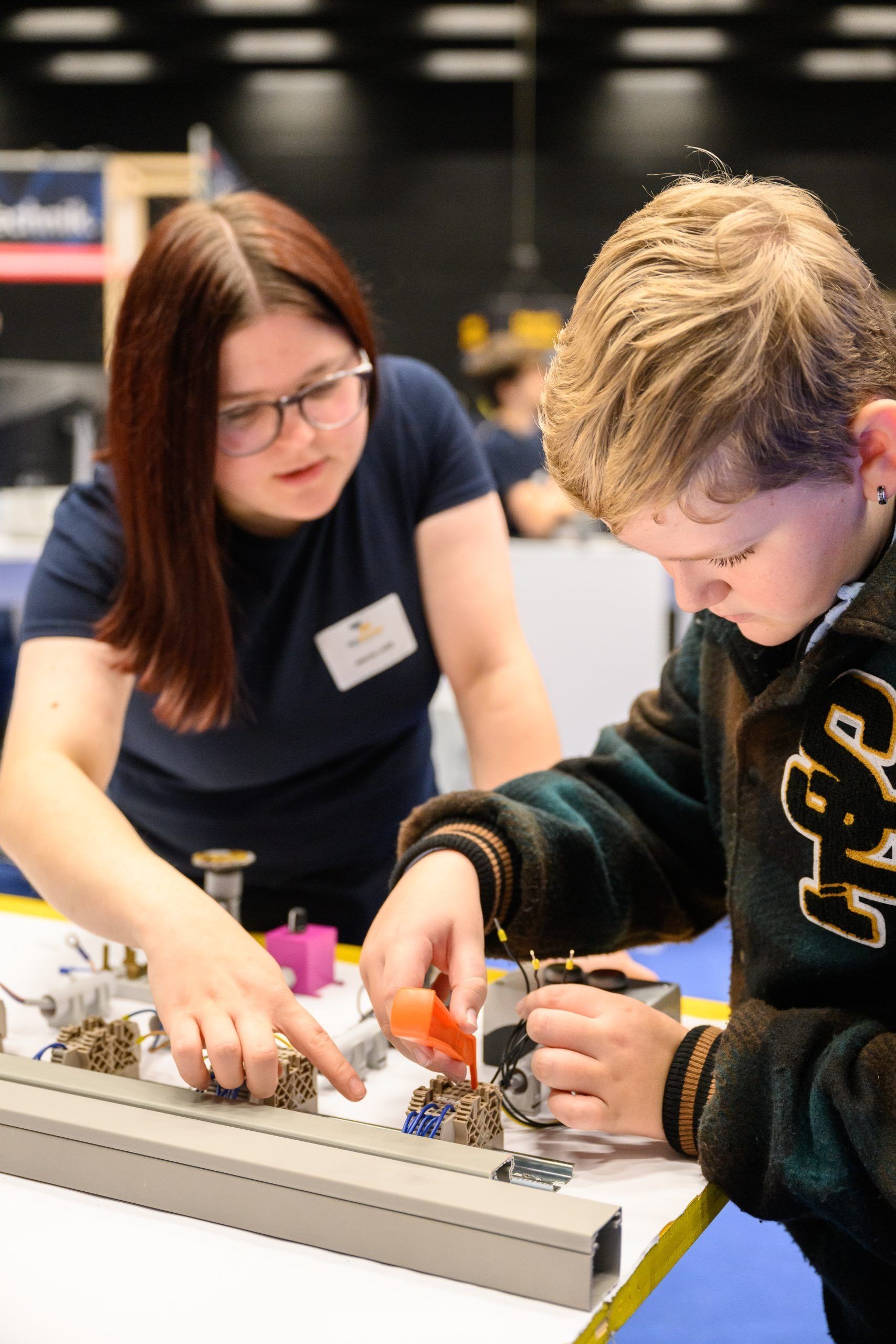 Frau und Kind arbeiten gemeinsam an einem Projekt an einem Tisch, beide konzentriert und engagiert.