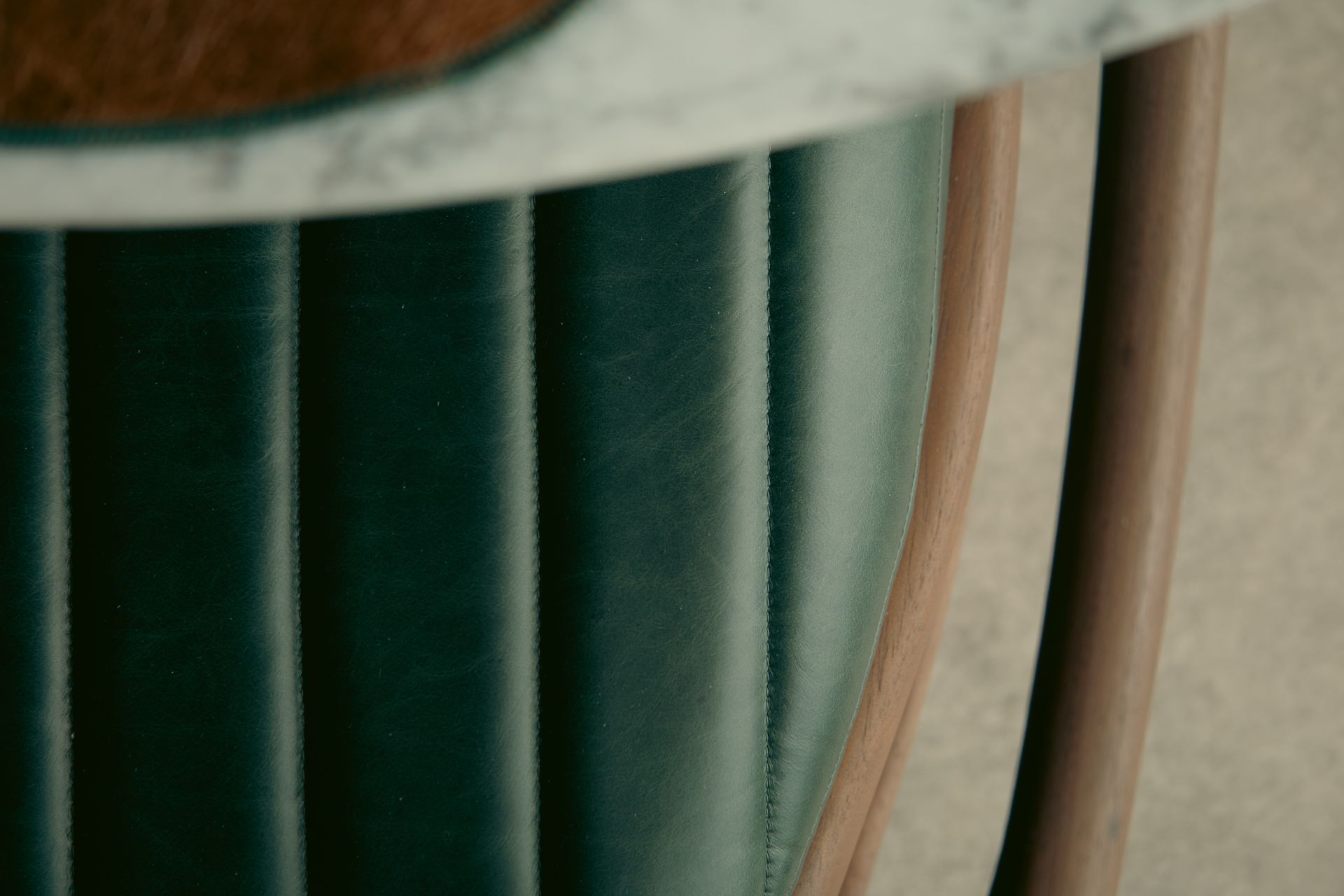 Um close de uma cadeira verde com tampo de mármore.