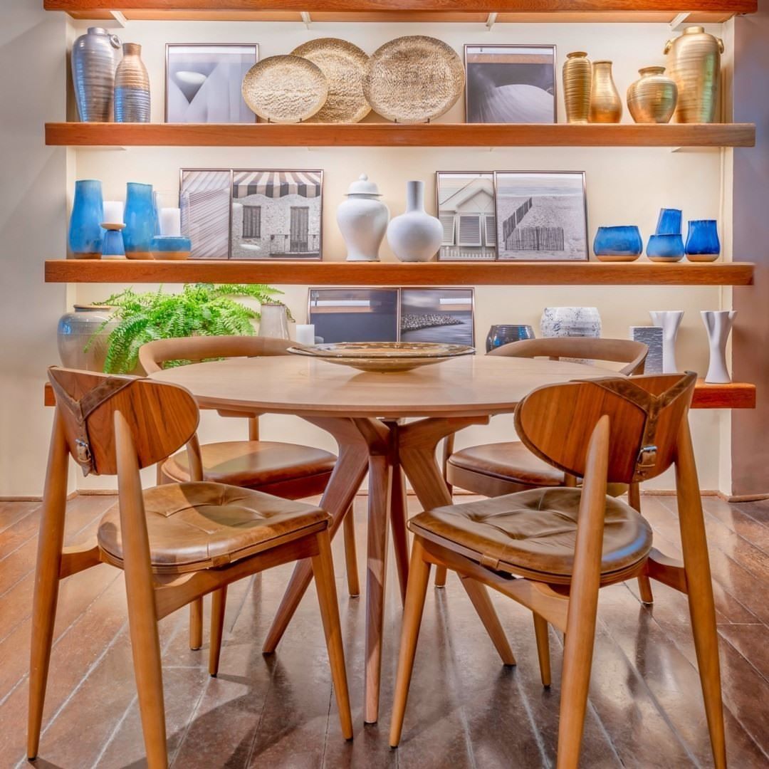 Uma mesa e cadeiras em frente a uma prateleira cheia de vasos