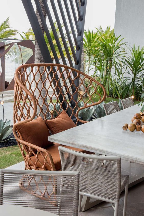 Uma cadeira de vime está ao lado de uma mesa em um pátio.