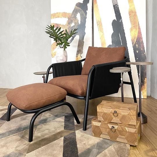 Uma cadeira e um pufe estão sobre um tapete em uma sala de estar.