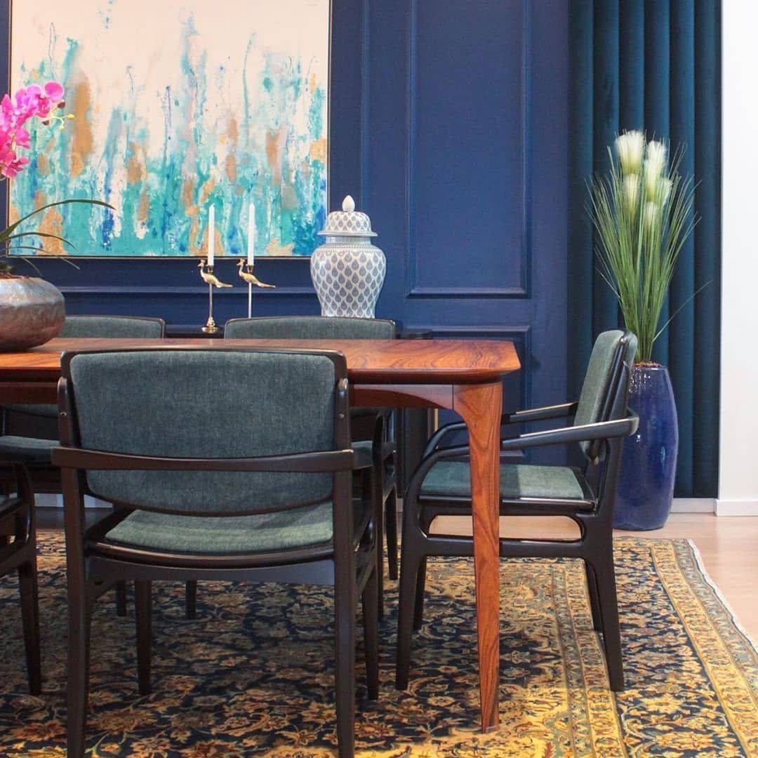 Uma sala de jantar com mesa e cadeiras e um quadro na parede.