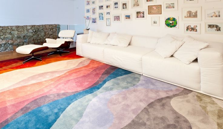 Sala com sofá branco e tapete colorido no chão.