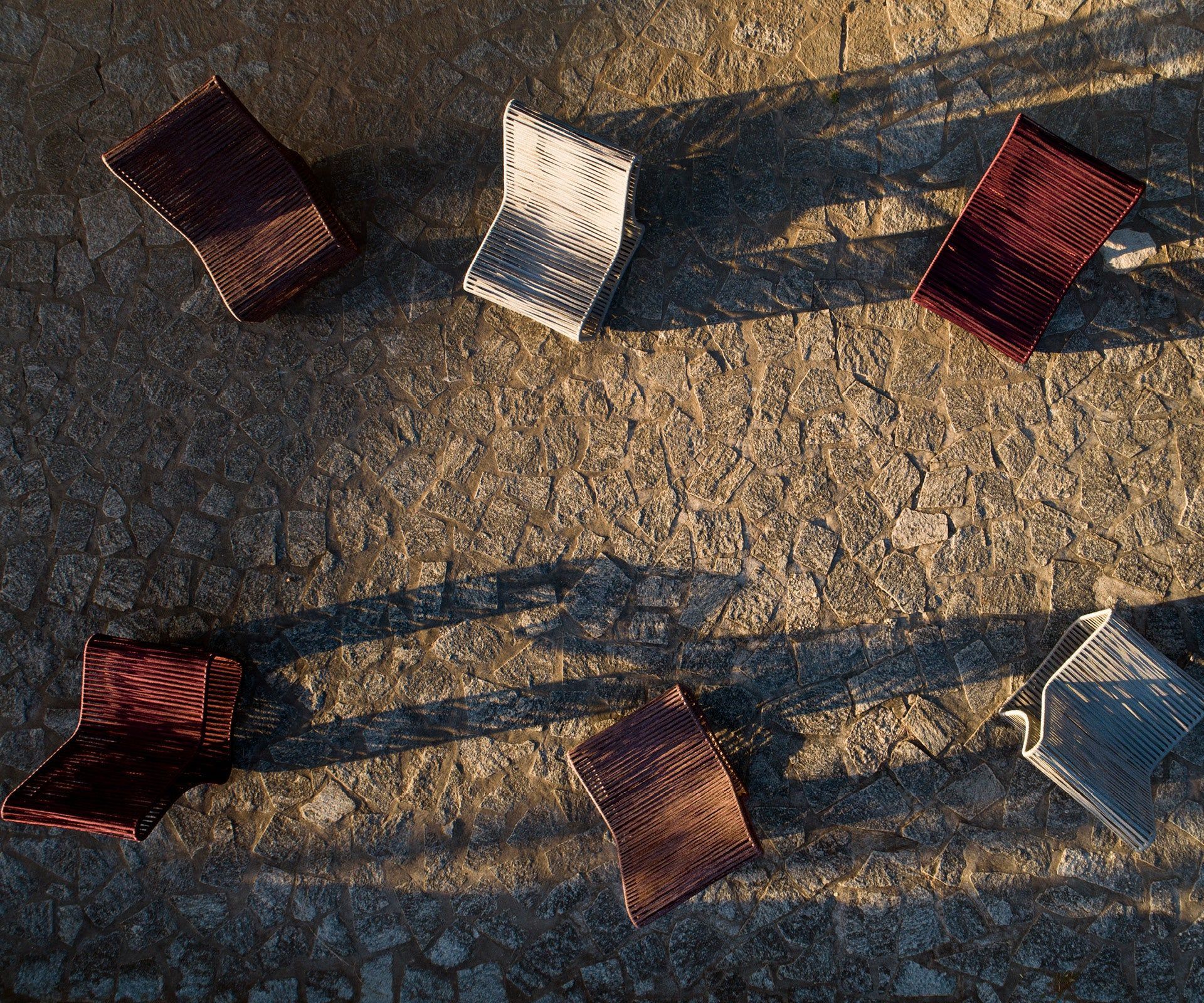 Um grupo de cadeiras está sentado em uma rua de paralelepípedos.