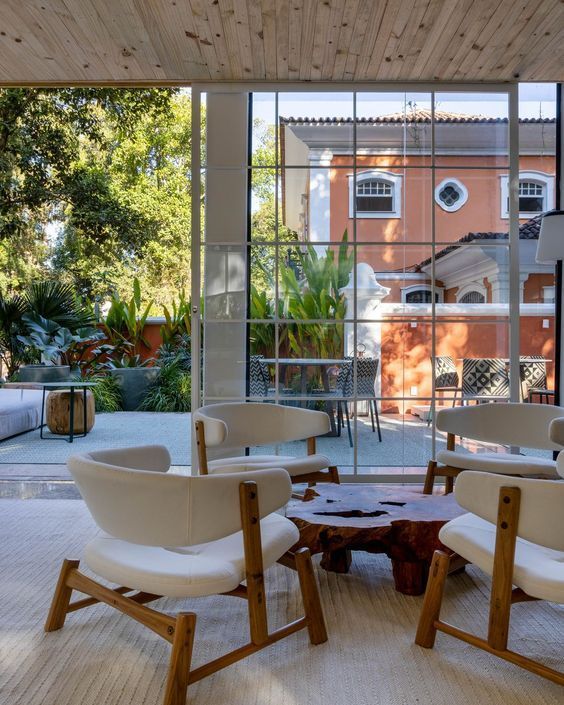 Uma sala de estar com cadeiras e mesa em frente a uma grande janela