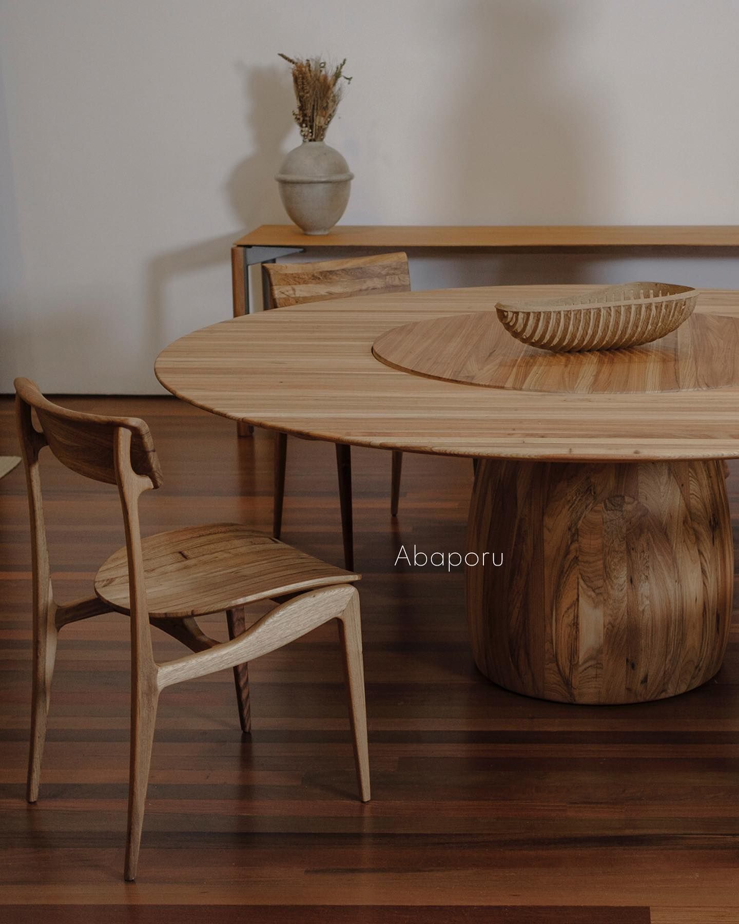 Uma mesa e cadeiras de madeira estão apoiadas sobre um piso de madeira.