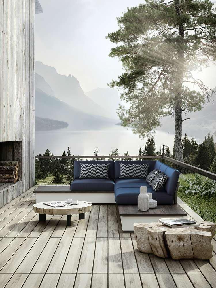 Um deck de madeira com um sofá secional azul e uma mesa de centro