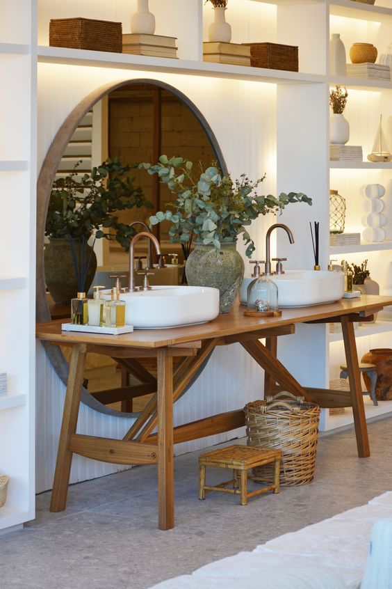 Banheiro com duas pias e espelho redondo.