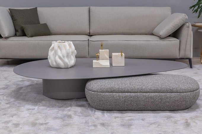 Uma sala de estar com sofá, mesa de centro e pufe.