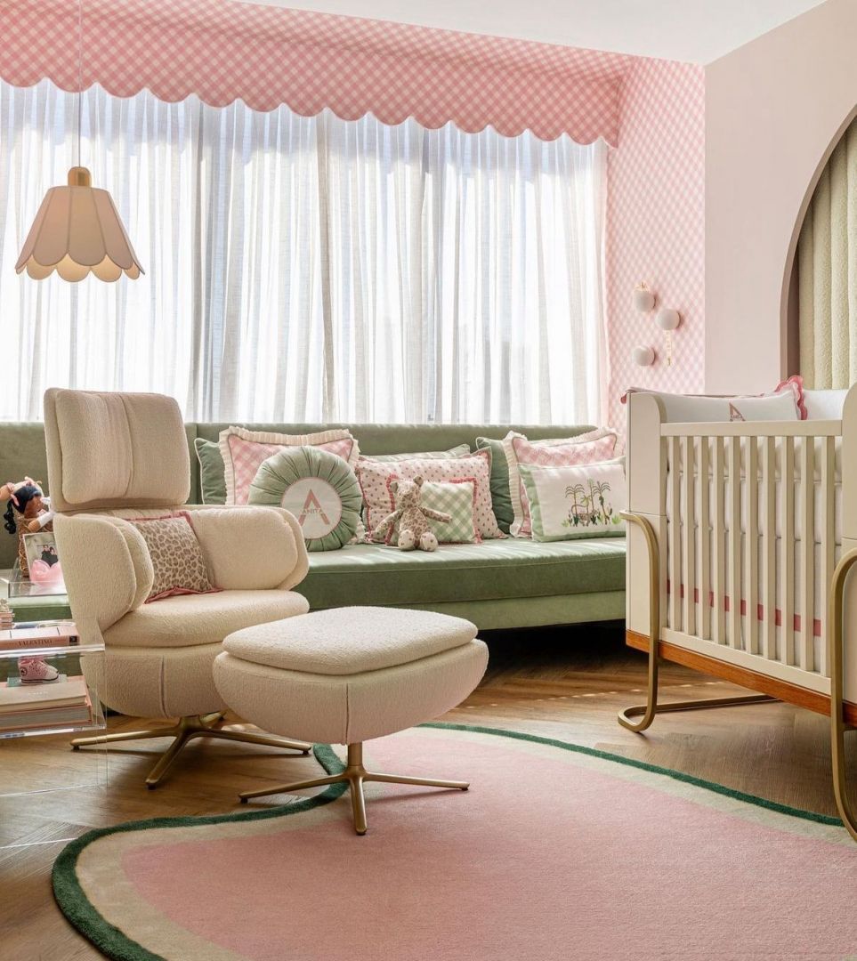 Uma sala de estar com sofá, cadeira, pufe e berço.