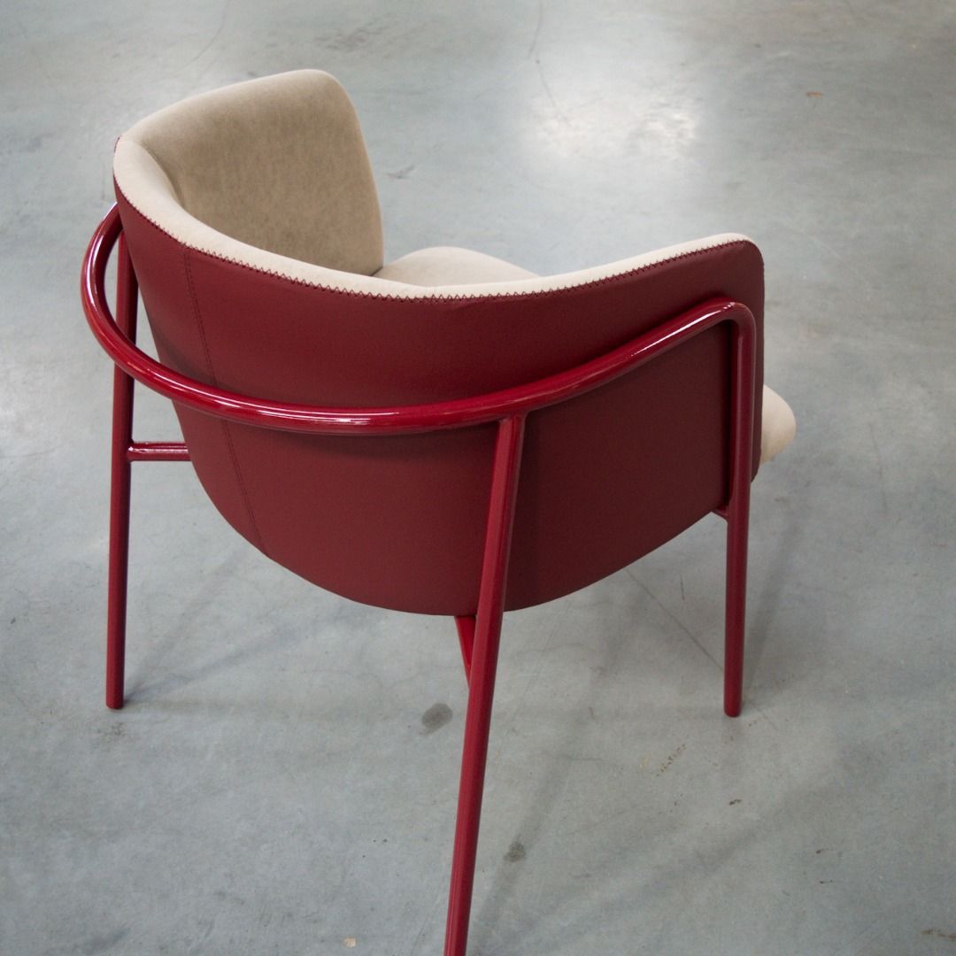 Uma cadeira vermelha está sentada num chão de concreto