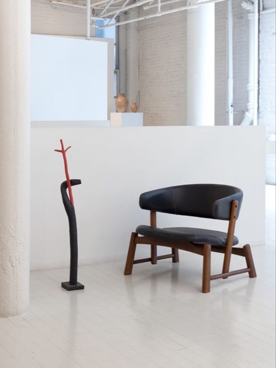 Uma cadeira está sentada em uma sala ao lado de uma estátua