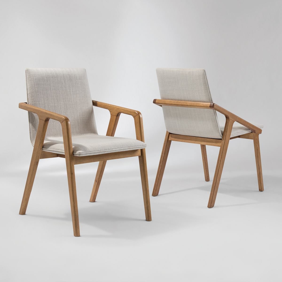 Duas cadeiras estão sentadas uma ao lado da outra sobre uma superfície branca.