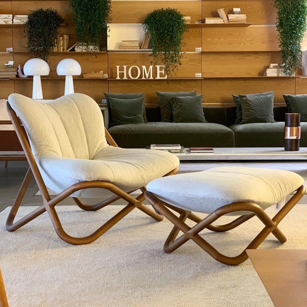 Uma sala de estar com cadeira e pufe e uma placa que diz casa