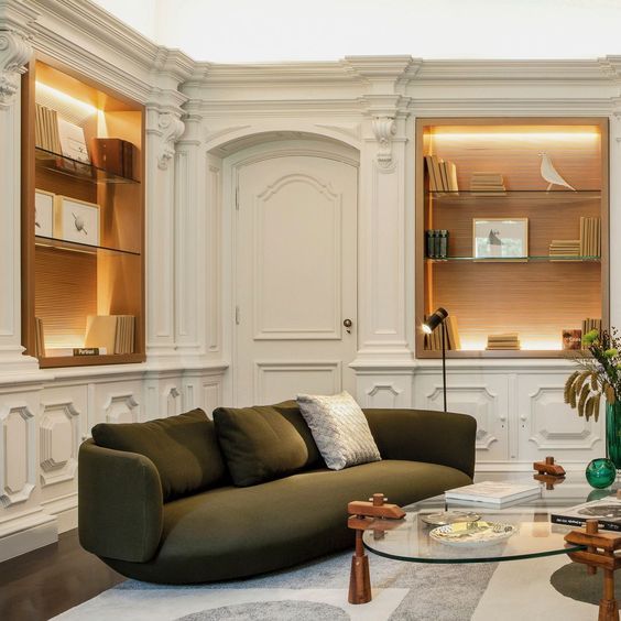 Uma sala de estar com sofá verde e mesa de centro de vidro