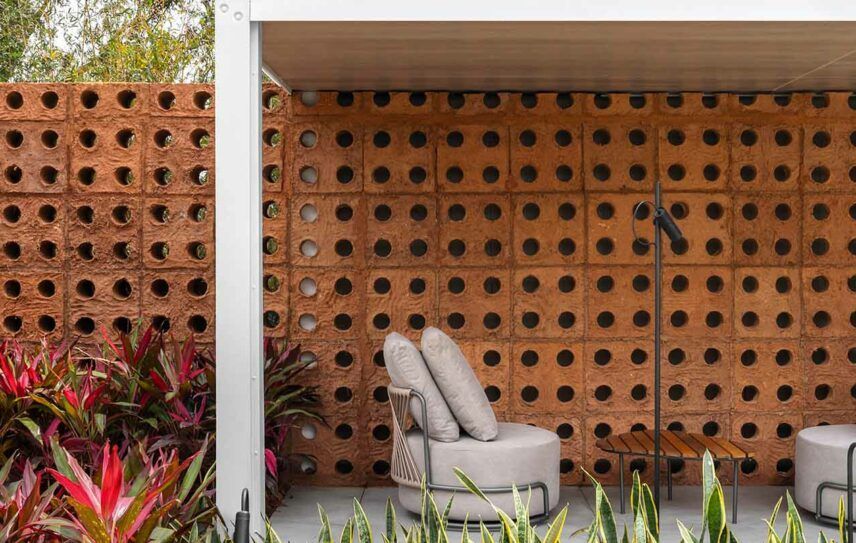 Há uma cadeira e uma mesa em frente a uma parede de tijolos.