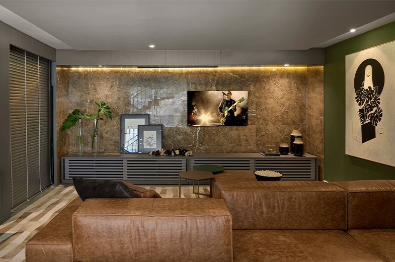 Sala de estar com sofá de couro marrom e televisão na parede.