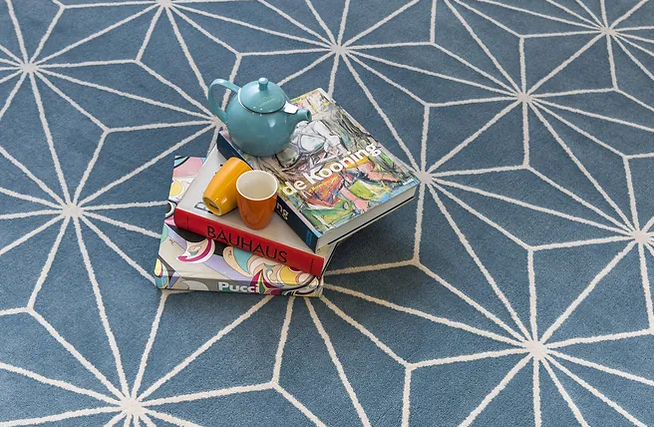 Uma pilha de livros e um bule sobre um tapete azul