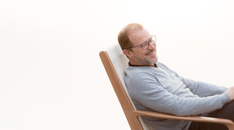 Um homem está sentado em uma cadeira com óculos.