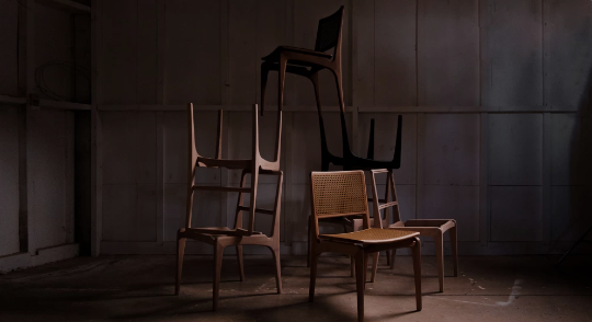 Três cadeiras estão empilhadas umas sobre as outras em uma sala escura.