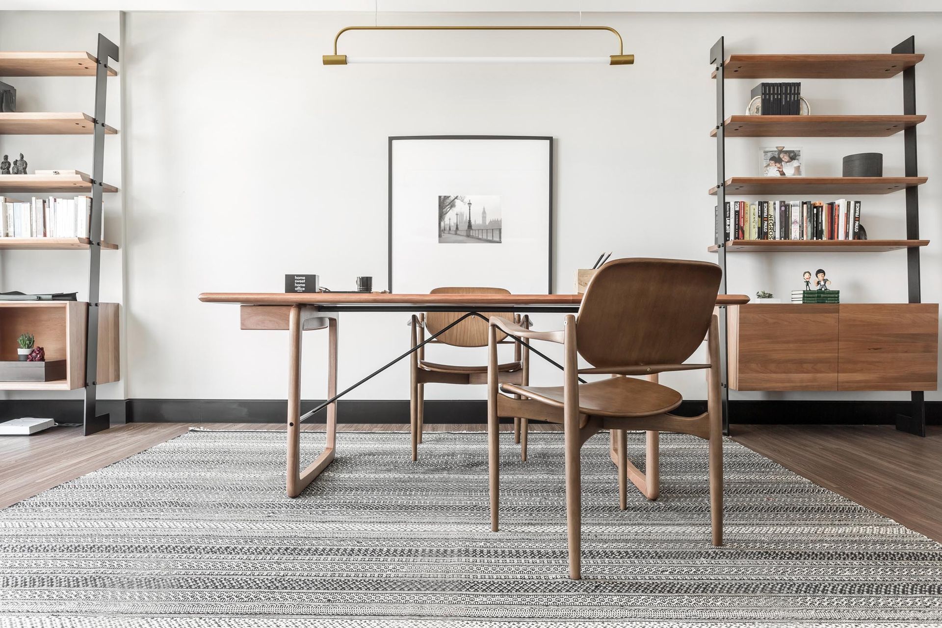 Um home office com mesa, cadeiras, estantes e tapete.