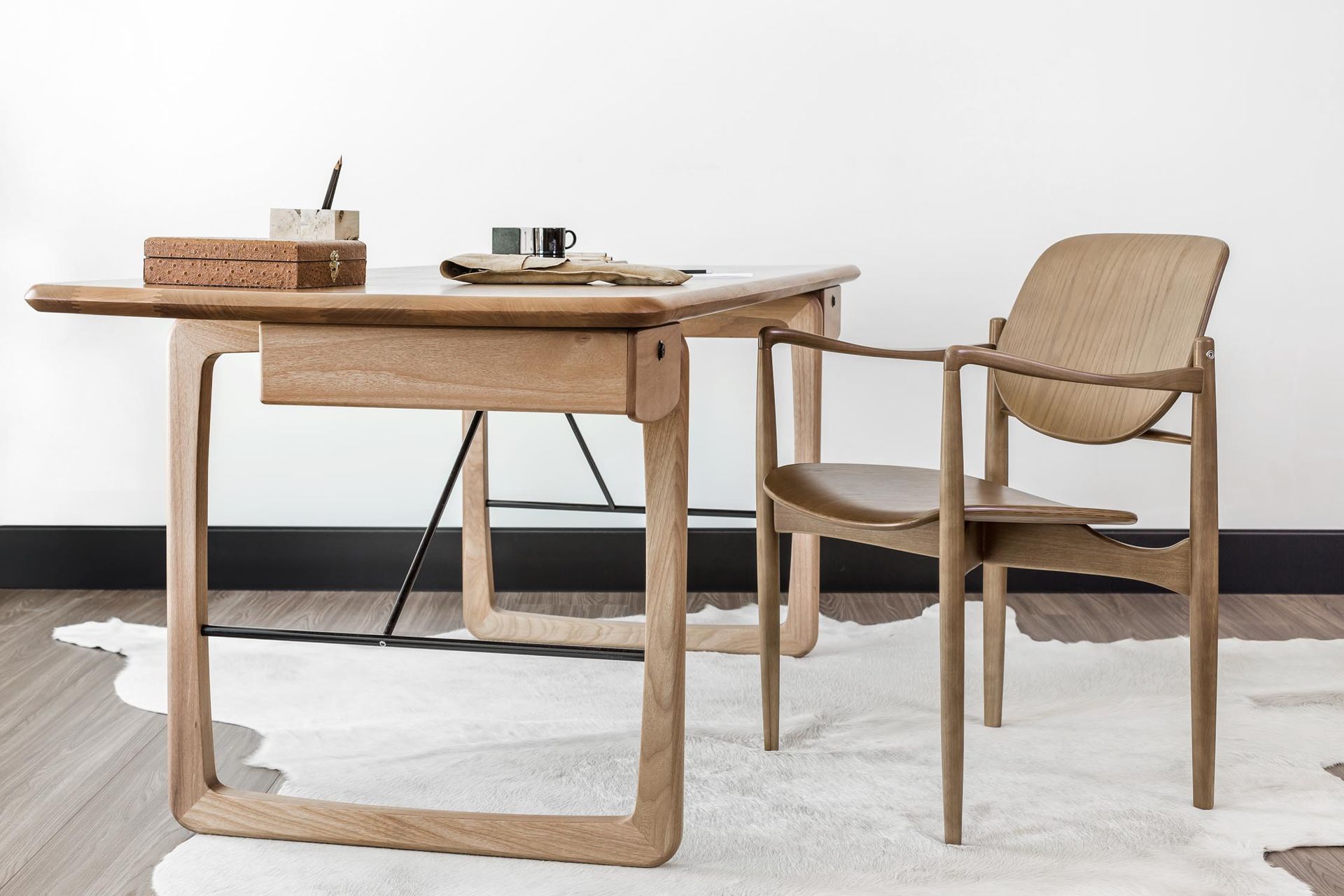 Uma mesa e uma cadeira de madeira estão sobre um tapete branco.