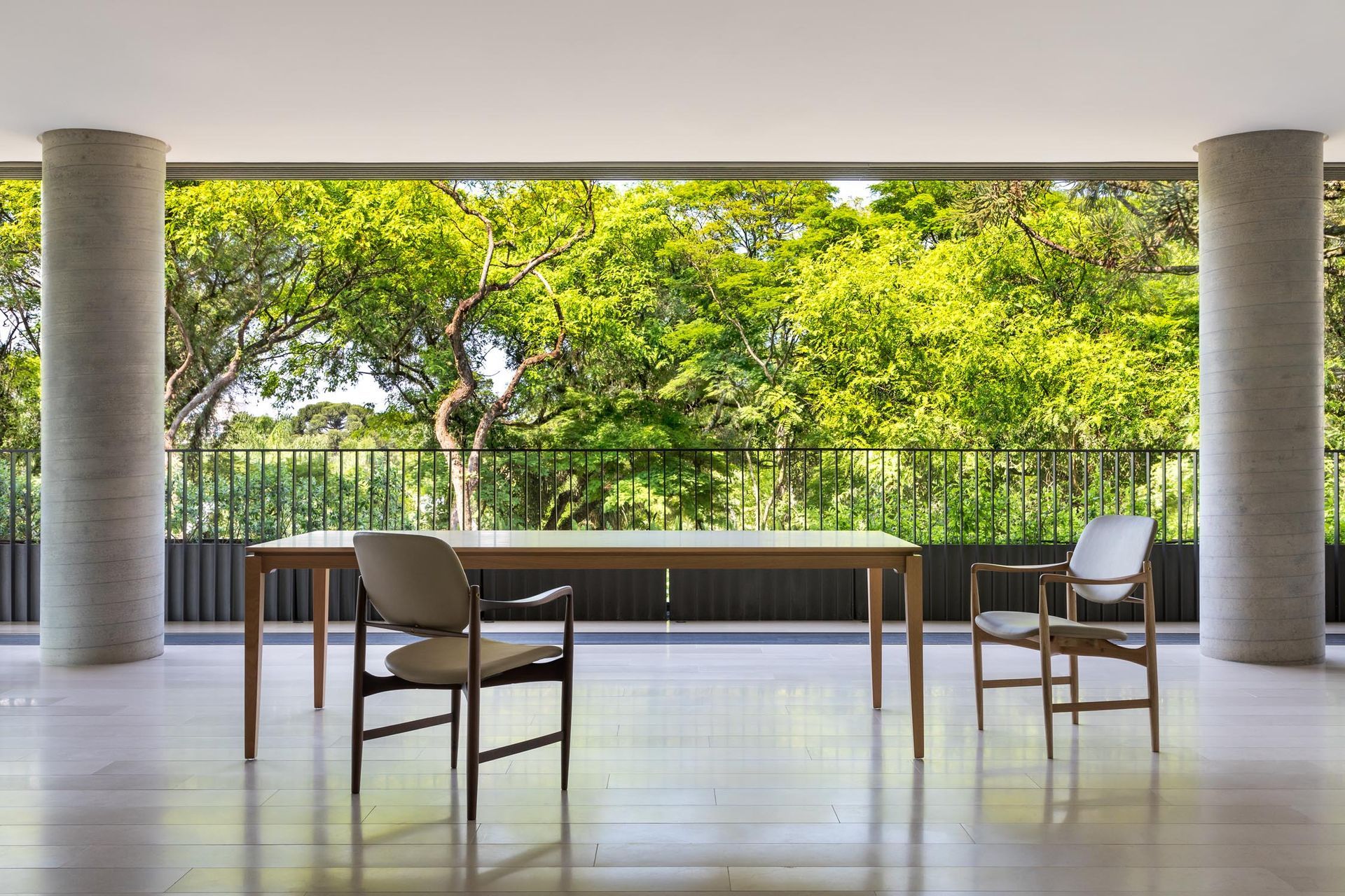 Uma mesa e cadeiras em uma varanda com árvores ao fundo