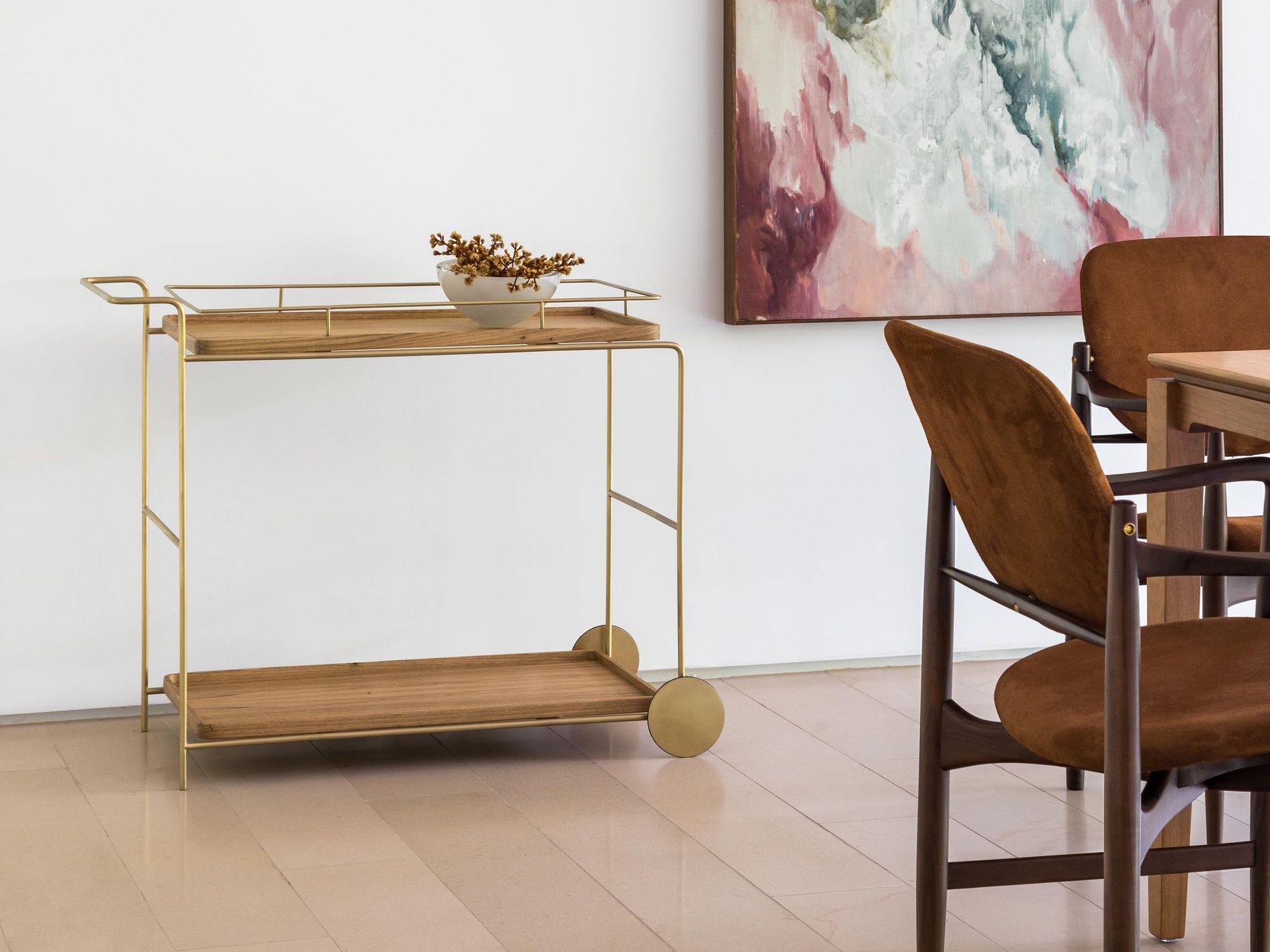 Um carrinho de madeira está em uma sala de jantar ao lado de uma mesa e cadeiras.